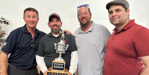 Four people pose with golf trophy